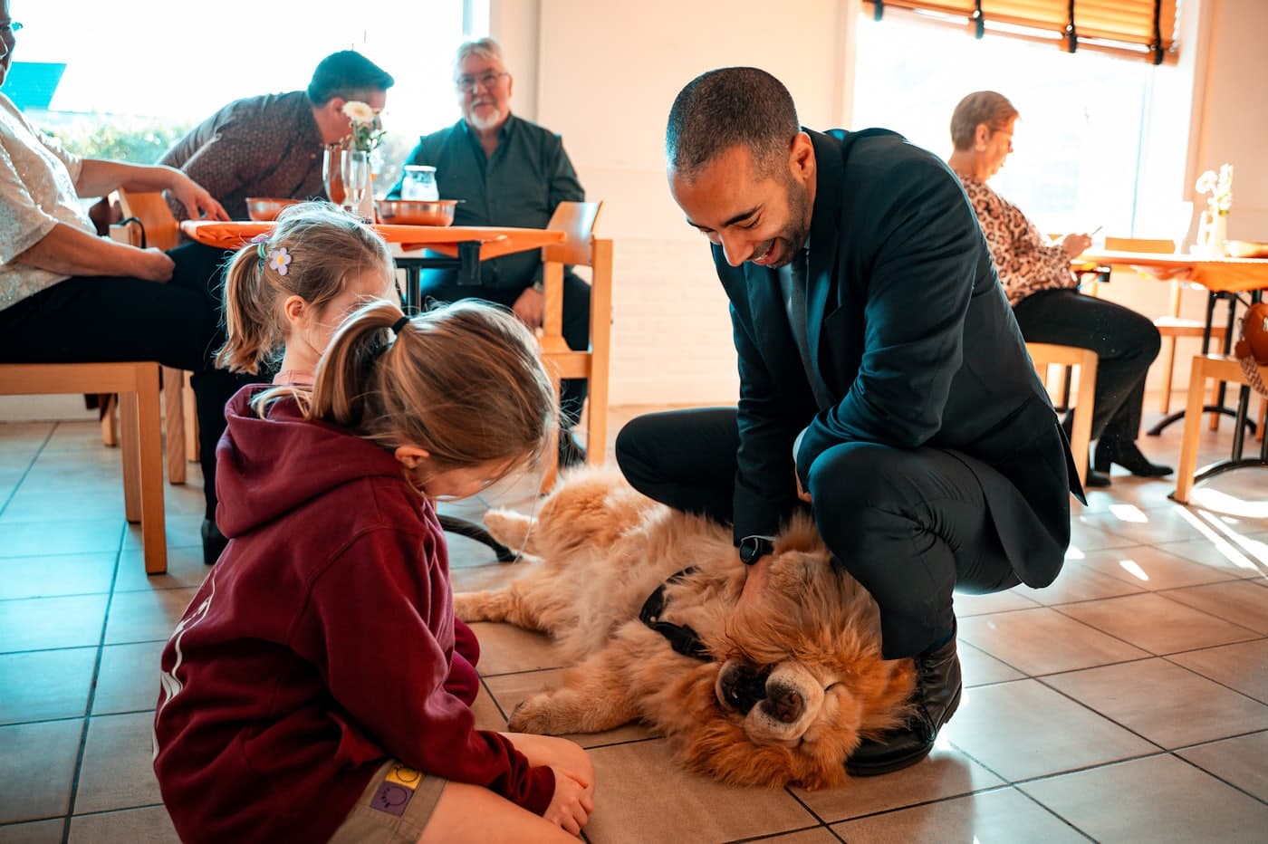 A man and two children together on the floor with their dog